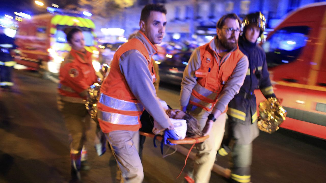 A woman is being evacuated from the Bataclan theater after a shooting in Paris, Friday Nov. 13, 2015.  French President Francois Hollande declared a state of emergency and announced that he was closing the country's borders. (AP Photo/Thibault Camus)