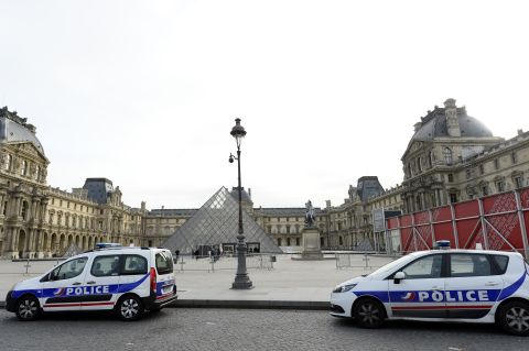 Police vehicles are parked near the entrance to the Louvre in Paris on November 14. Interior Minister Bernard Cazeneuve said the state of emergency in France could mean restrictions on people's movements. Airports in France remained open, and airlines were still flying there, though some airlines reported canceled flights. 