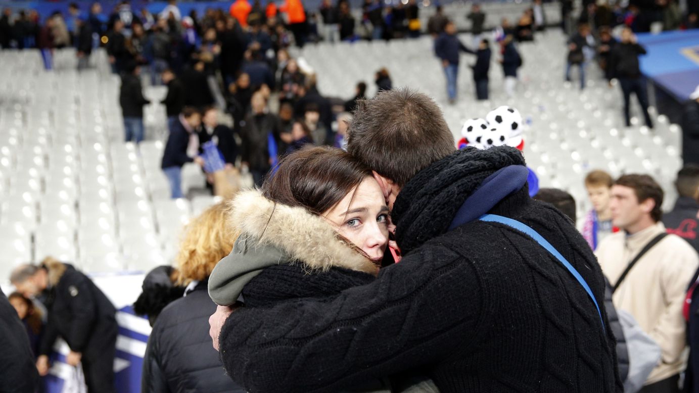 Spectators embrace each other as they stand on the playing field of the Stade de France stadium at the end of a soccer match between France and Germany in Saint-Denis, outside Paris, on November 13.