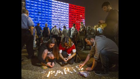 People in Tel Aviv, Israel, light candles and hold posters during a gathering to honor the victims of the Paris attacks on November 14.