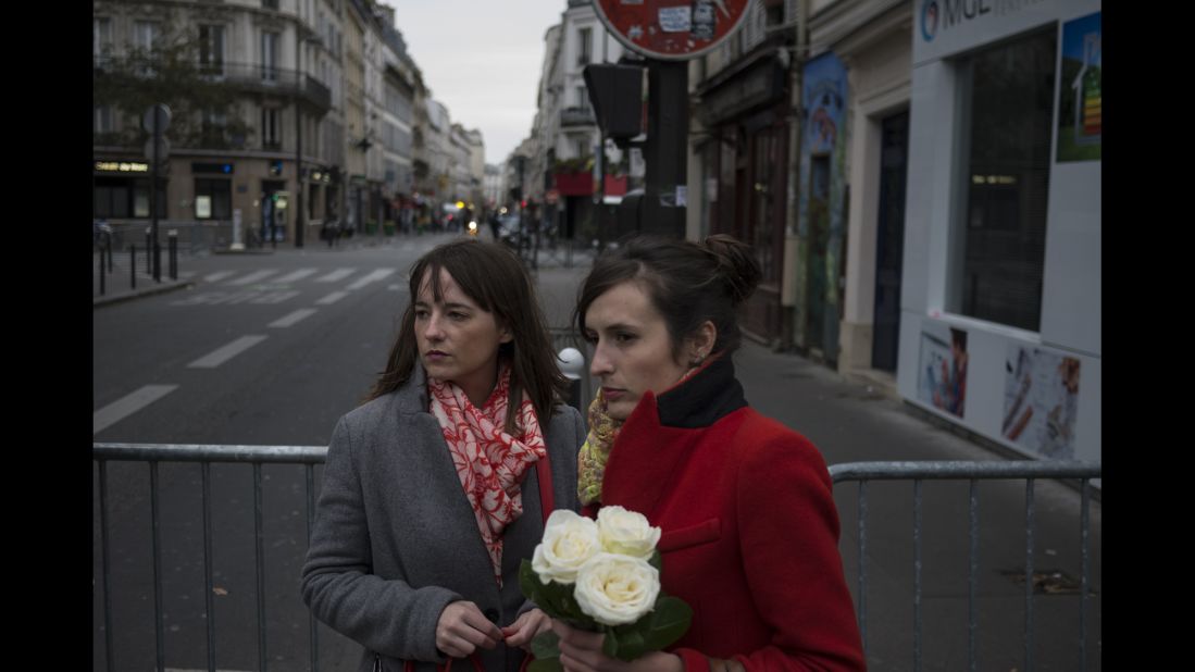 Women pay their respects near the Bataclan on November 14. Three gunmen shot concertgoers and held hostages late Friday night until police raided the building.