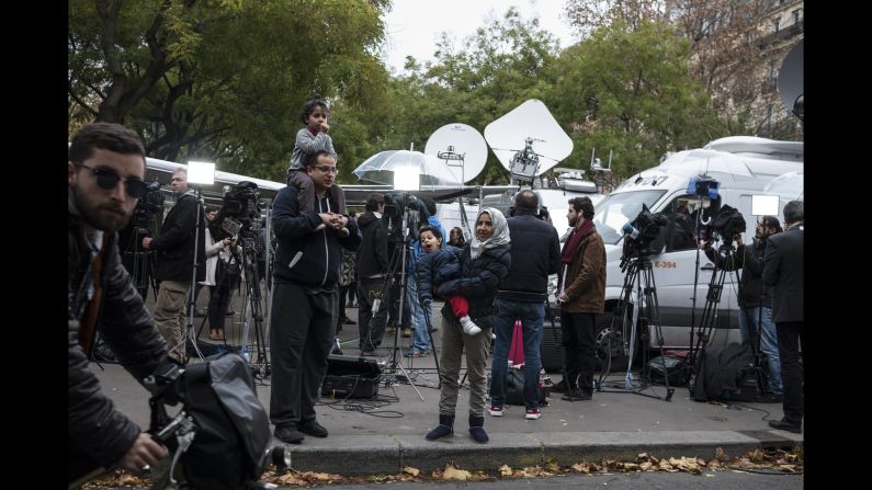 A family stands among TV crews set up on November 14 near the Bataclan.