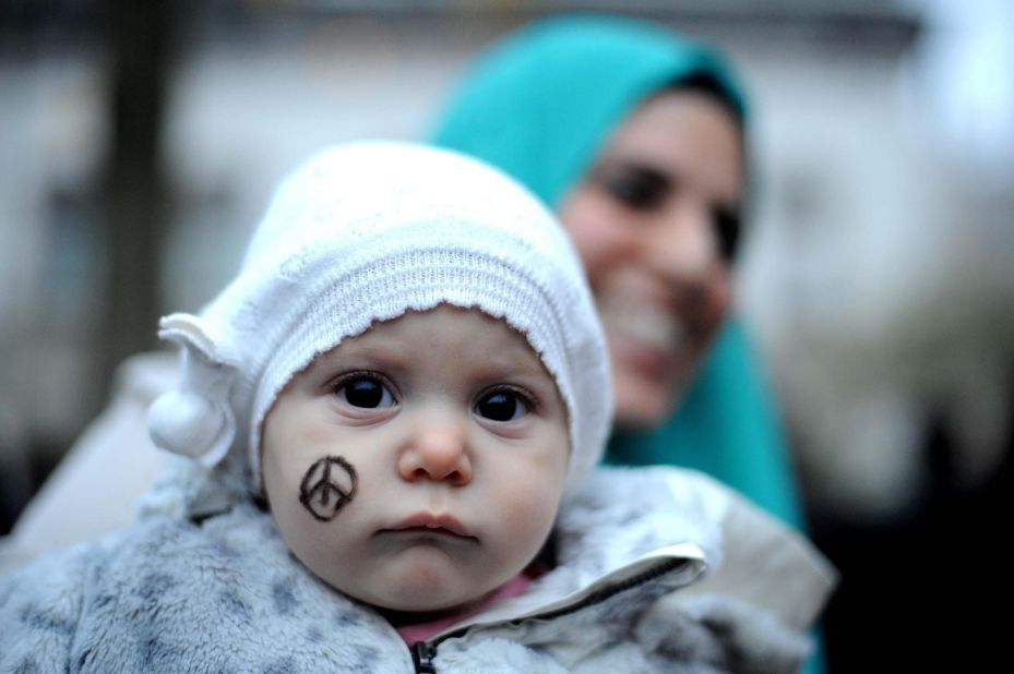 A baby is spotted with a peace symbol of the Eiffel Tower on her cheek, as people gather in a solidarity rally with the French people in Milan, Italy on Saturday.