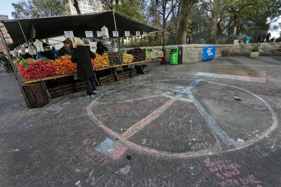 A woman shops for produce next to a peace sign drawn in solidarity to the people of Paris in New York's Union Square on Saturday, a day after the attacks.