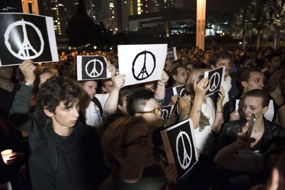 People hold peace signs as they gather during a memorial event in Hong Kong on November 14, 2015 for victims of the Paris terror attacks.
