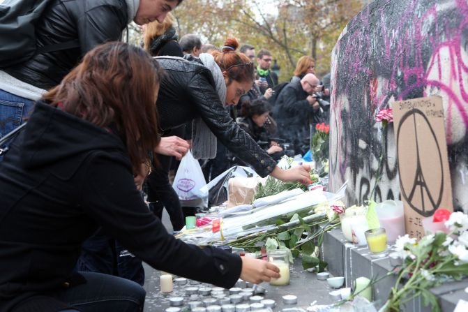 People gather around the statue of Marianne, symbol of the French Republic, to lay flowers and light candles in tribute to the victims of deadly attacks that struck Paris. 