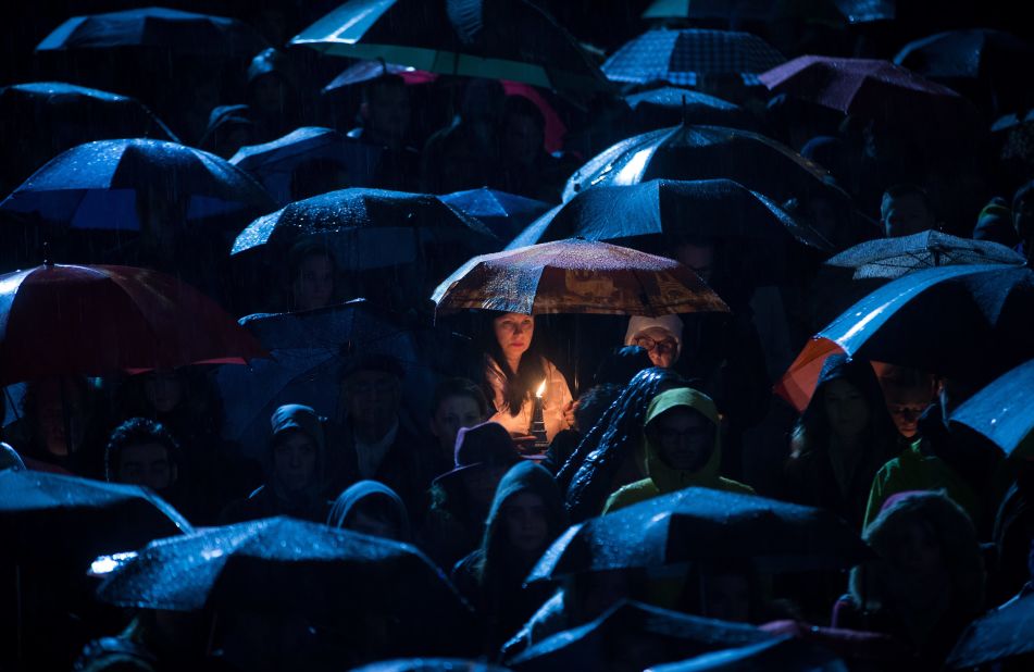 A woman holds a candle atop a miniature replica of the Eiffel Tower during a candlelight vigil Saturday, November 14, in Vancouver, British Columbia.