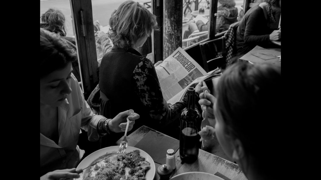 A woman reads a publication with bolded and capitalized letters spelling out l'horreur, while people all around her fork pieces of food from their plates. "People were standing outside, having their brunch or whatever, and literally 100 meters away, eight hours before, 18 people (were) being killed," Majoli said.<br />