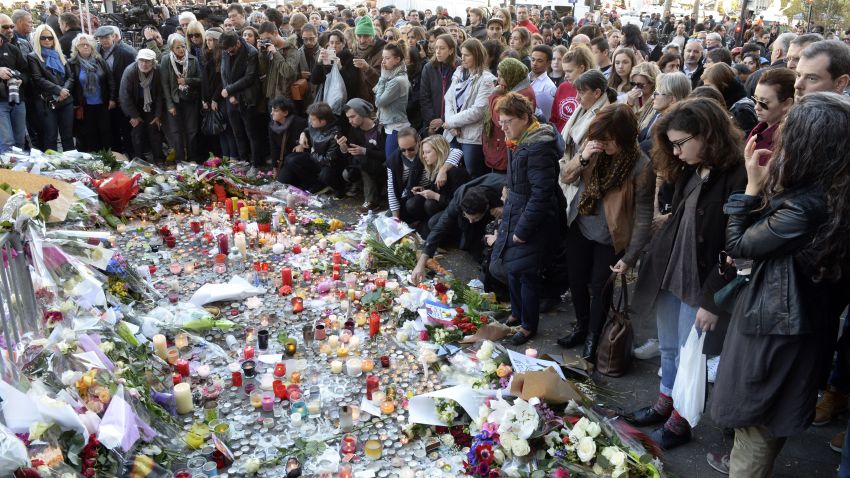 People gather at a memorial set-up along a police cordon close to the Bataclan concert hall on November 15, 2015, two days after a series of deadly attacks. Islamic State jihadists claimed a series of coordinated attacks by gunmen and suicide bombers in Paris on November 13 that killed at least 128 people in scenes of carnage at a concert hall, restaurants and the national stadium. AFP PHOTO / MIGUEL MEDINA        (Photo credit should read MIGUEL MEDINA/AFP/Getty Images)