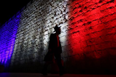 A man walks past Jerusalem's Old City walls, which were illuminated in the colors of the French flag on November 15.