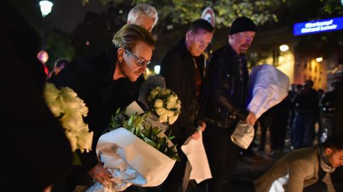 Bono, left, and members of U2 place flowers near the Bataclan Theatre in Paris on Saturday.
