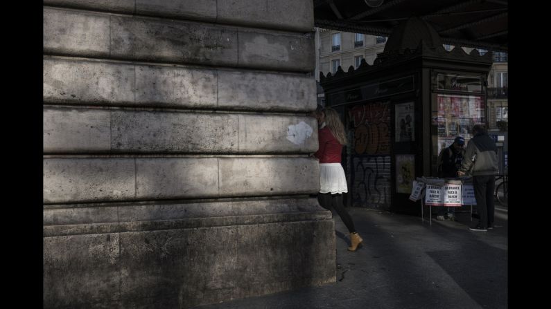 People walk past a man selling newspapers near the Barbes-Rochechouart Metro station on November 15.
