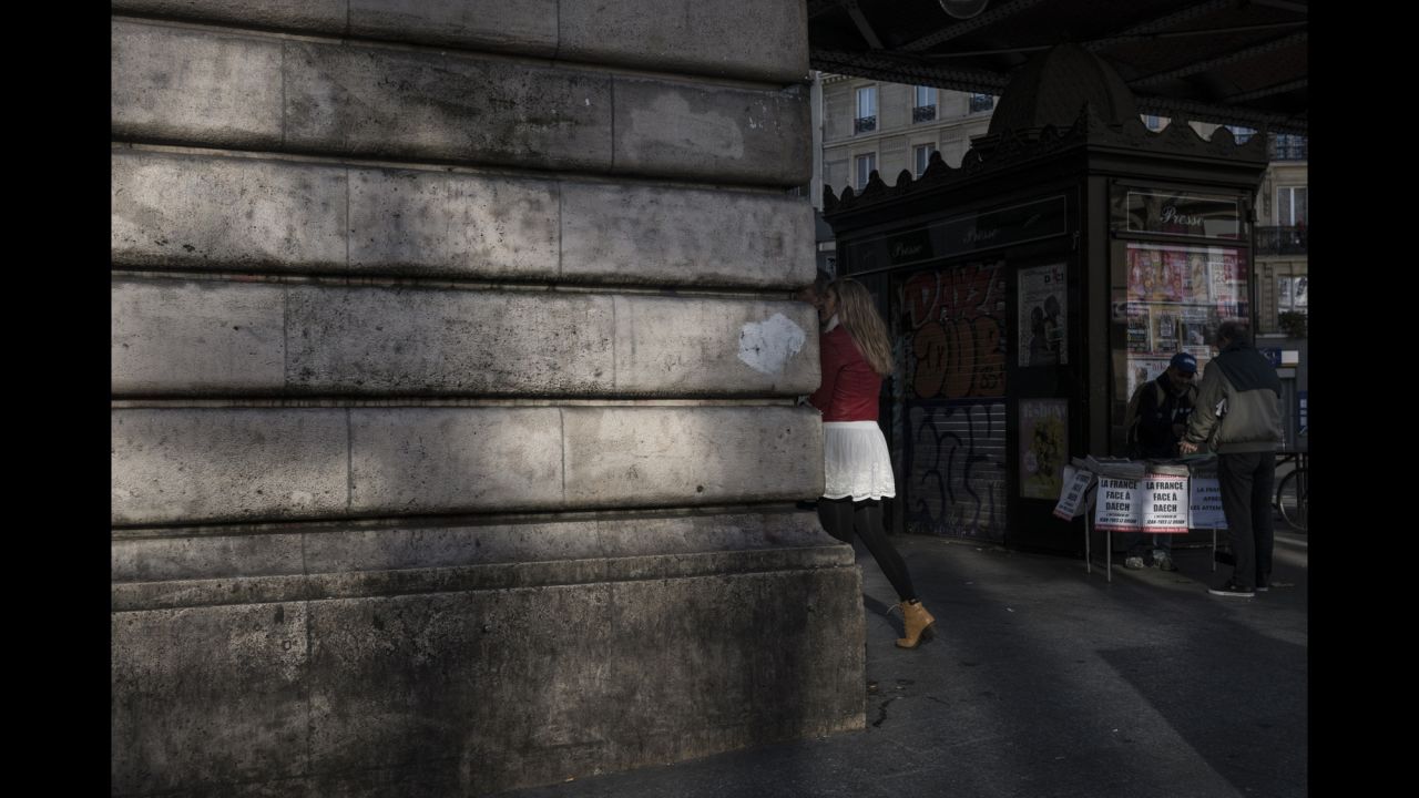People walk past a man selling newspapers near the Barbes-Rochechouart Metro station on November 15. 