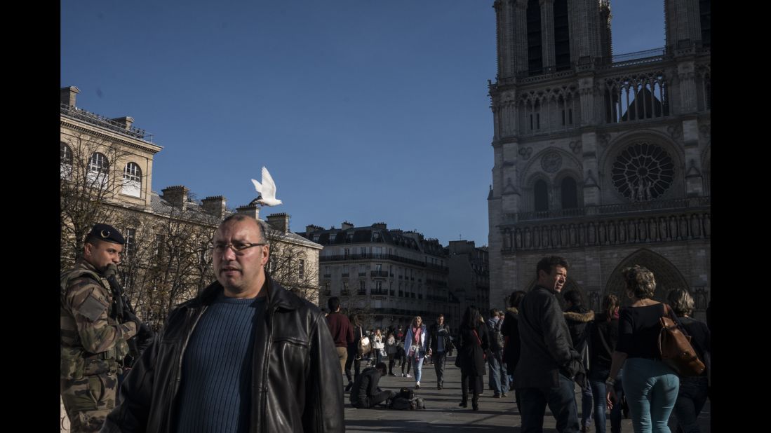 Tourists walk past Notre Dame on November 15 as the military and police patrol the area. 