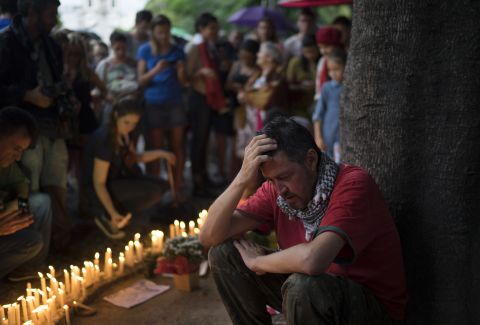 A man sits next to candles lit as homage to the victims of the deadly attacks in Paris at a square in Rio de Janeiro on November 15.