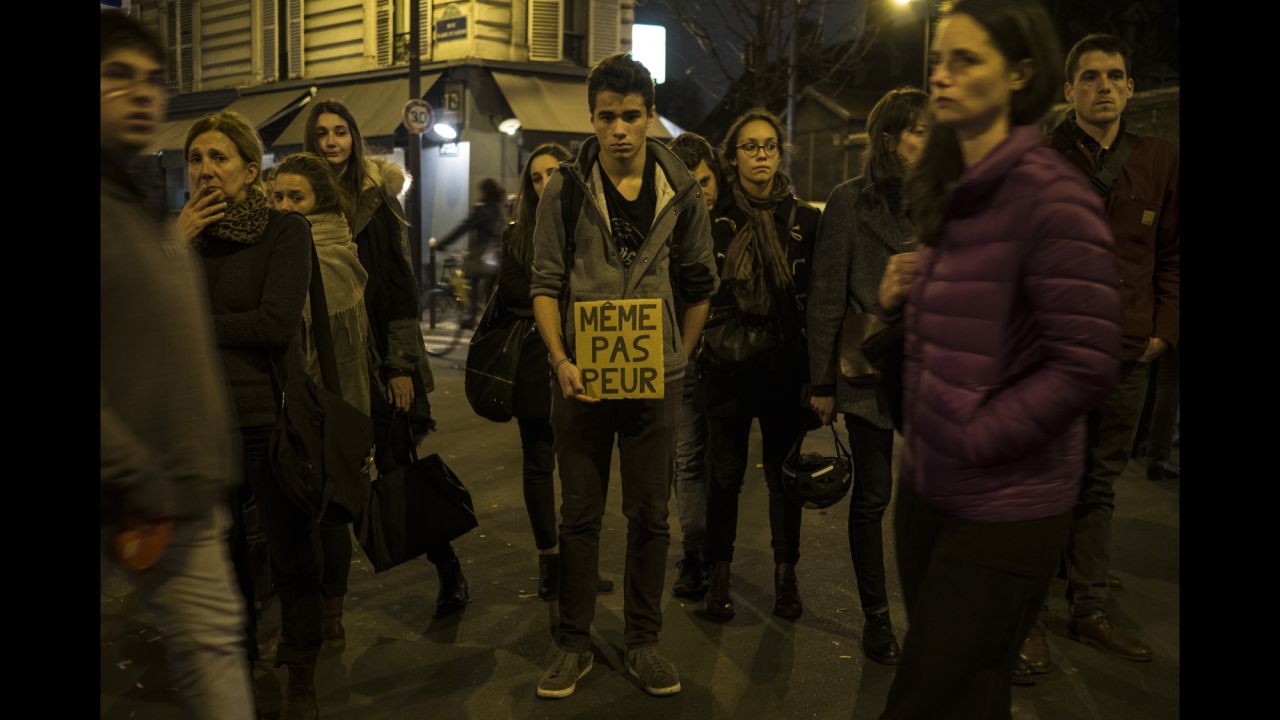 A young man in Paris on November 16 holds a sign that reads "Not even afraid" in the neighborhood of Le petit Cambodge, a restaurant that was hit in the attacks.