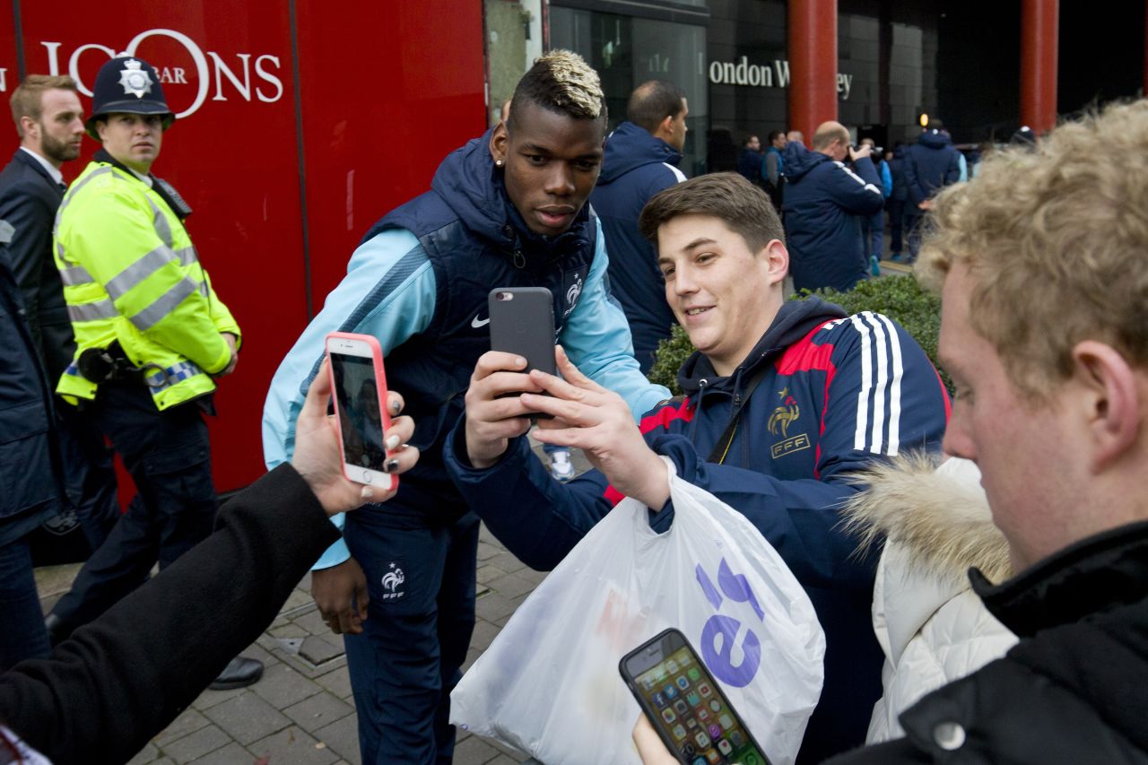 France midfielder Paul Pogba (C) stops to have a selfie taken with a supporter.