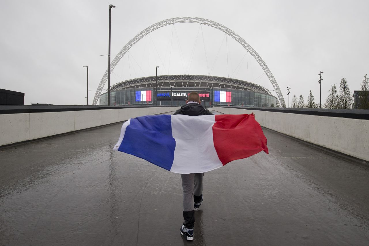 A French football fan, draped in the national flag, walks towards Wembley Stadium in London, ahead of the international friendly football match between England and France.