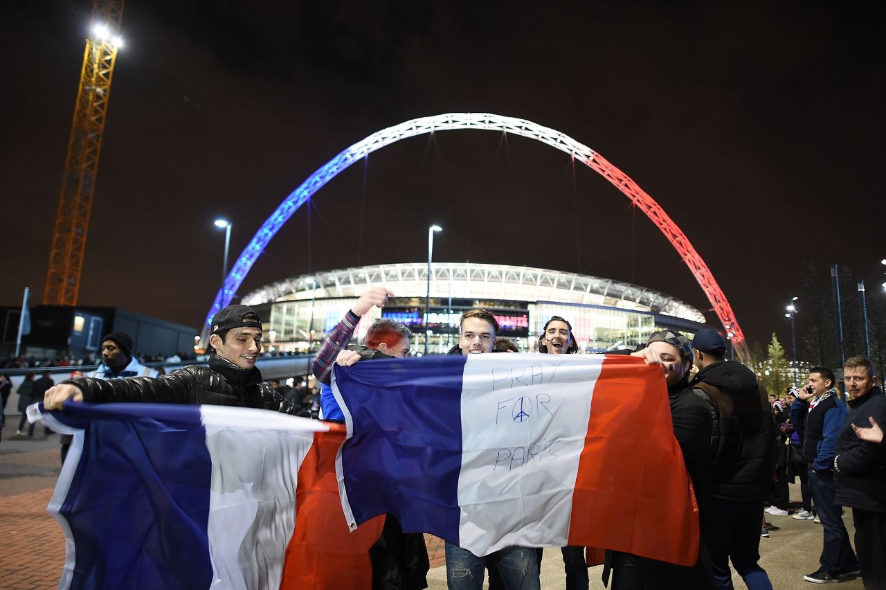 Fans pose in front of Wembley's Stadium arch, which is lit up in the French flag's colors, ahead of the international friendly between England and France Tuesday. Security in London has been tightened after a series of terror attacks across the French capital of Paris Friday, leaving at least 129 people dead and hundreds more injured.