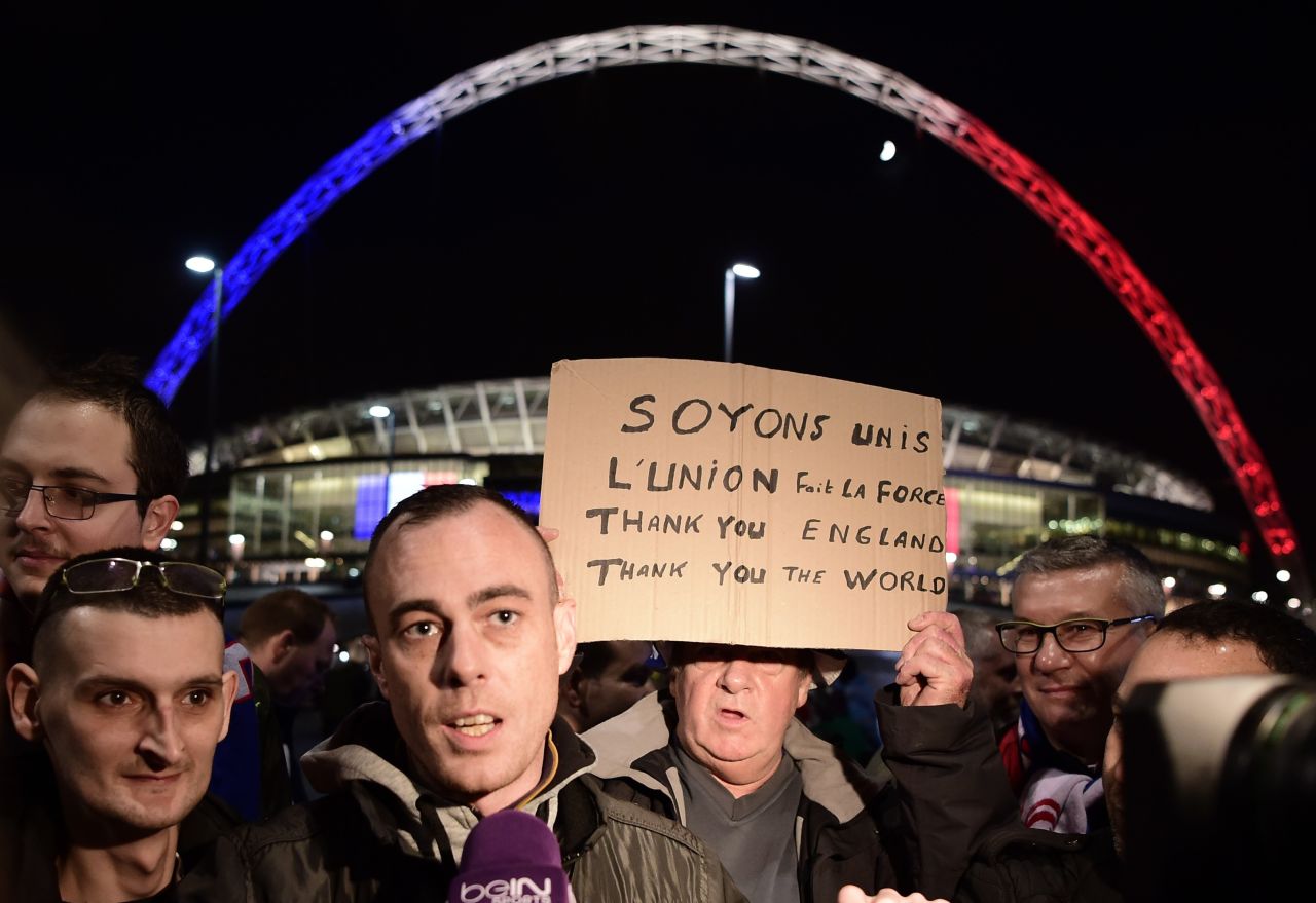 Football supporters holding a message of thanks are interviewed by the media outside Wembley Stadium.