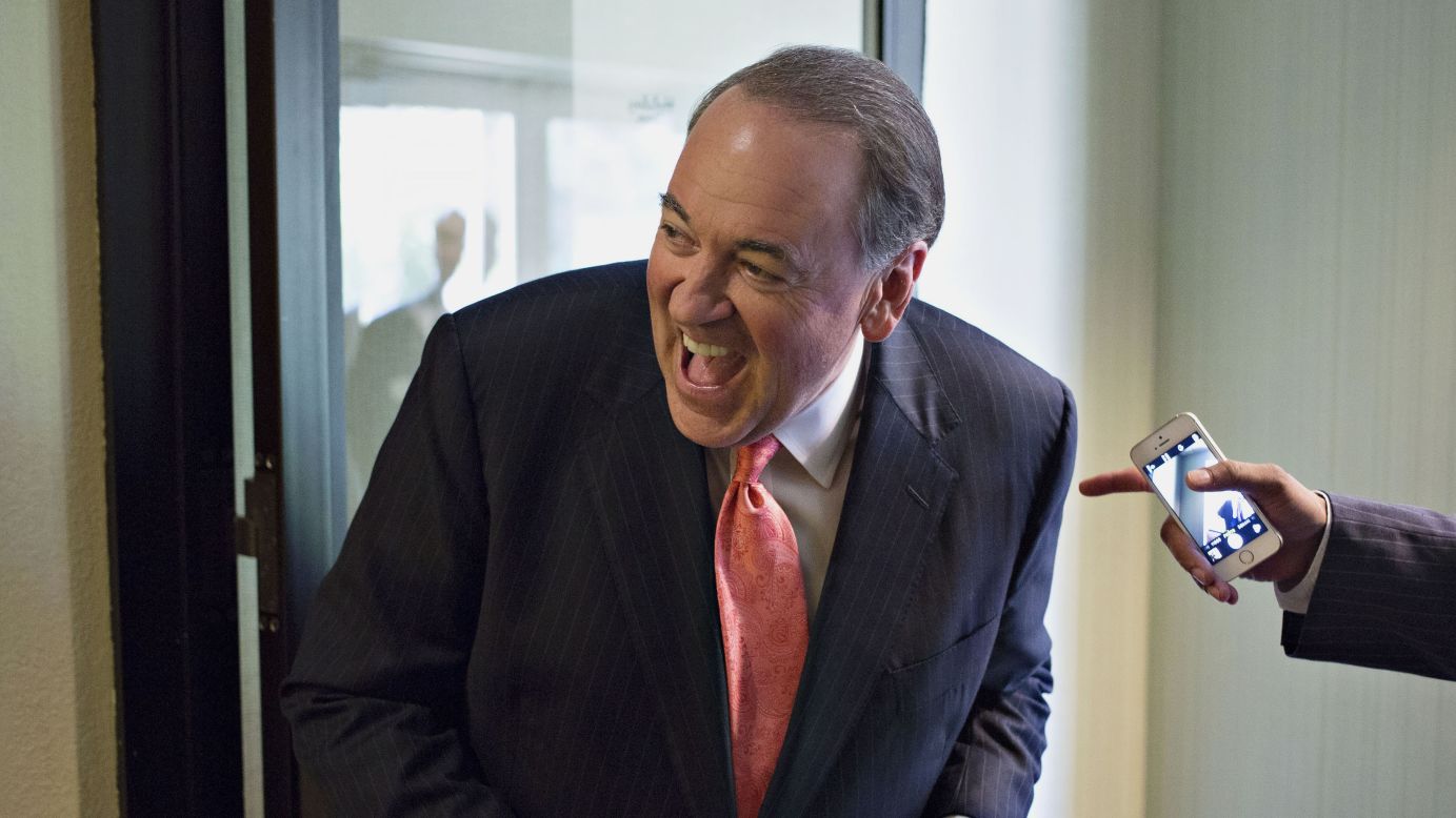 Republican presidential candidate Mike Huckabee laughs with a staff member Friday, July 31, while attending the RISE Initiative black Christian summit in Tinley Park, Illinois.