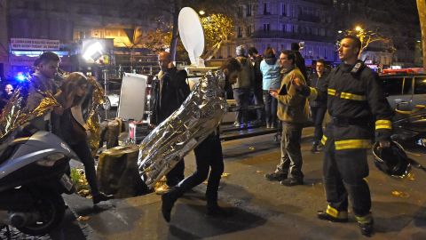 People wearing survival blankets walk from the Bataclan.