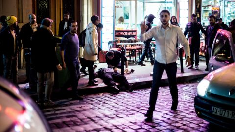 A crowd gathers outside Café Bonne Bière as a man lies on the pavement.