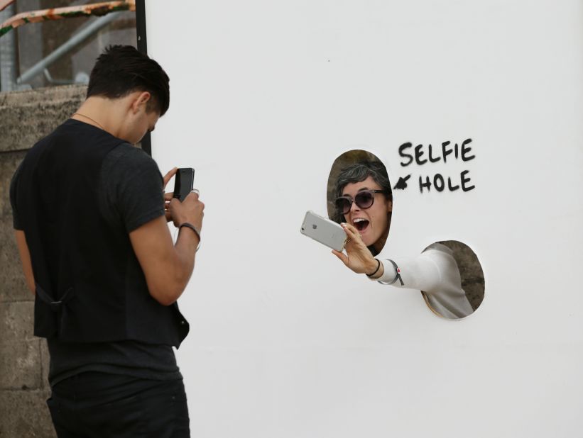 A visitor photographs herself through a "selfie hole" at Banksy's "Dismaland," <a href="http://www.cnn.com/2015/08/20/arts/banksy-dismaland-art-exhibition/" target="_blank">a "bemusement park" exhibition</a> that opened Saturday, August 21, in Weston-super-Mare, England.