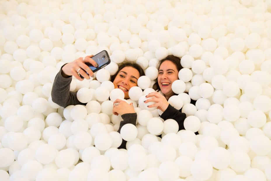 Visitors of "Jump In!" take photos inside the adults-only ball pit Wednesday, February 4, in London. The installation, which held more than 80,000 white balls, was at the Pearlfisher design agency.