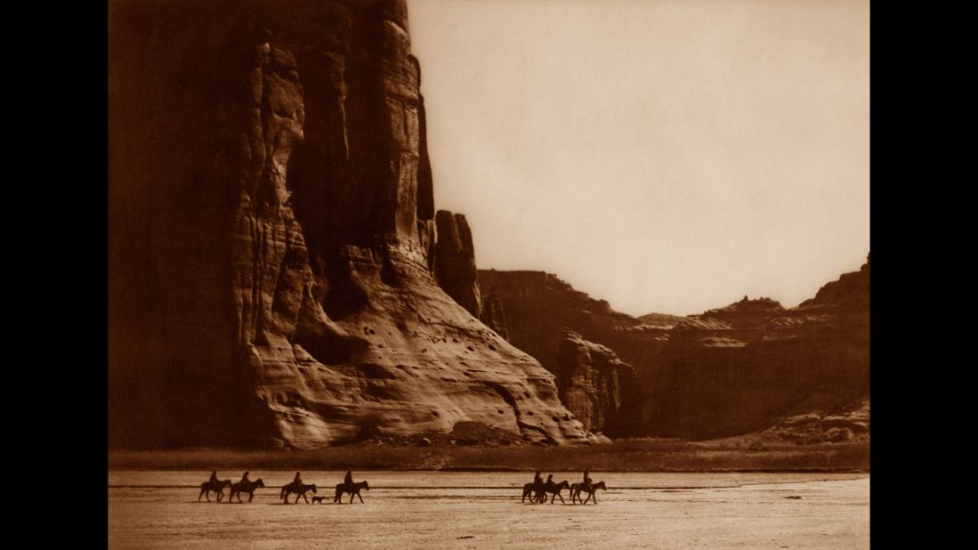 Navajo people ride horses by Arizona's Canyon de Chelly. 