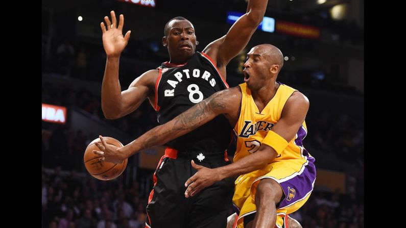 Kobe Bryant passes around Toronto defender Bismack Biyombo during an NBA game in Los Angeles on Friday, November 20.