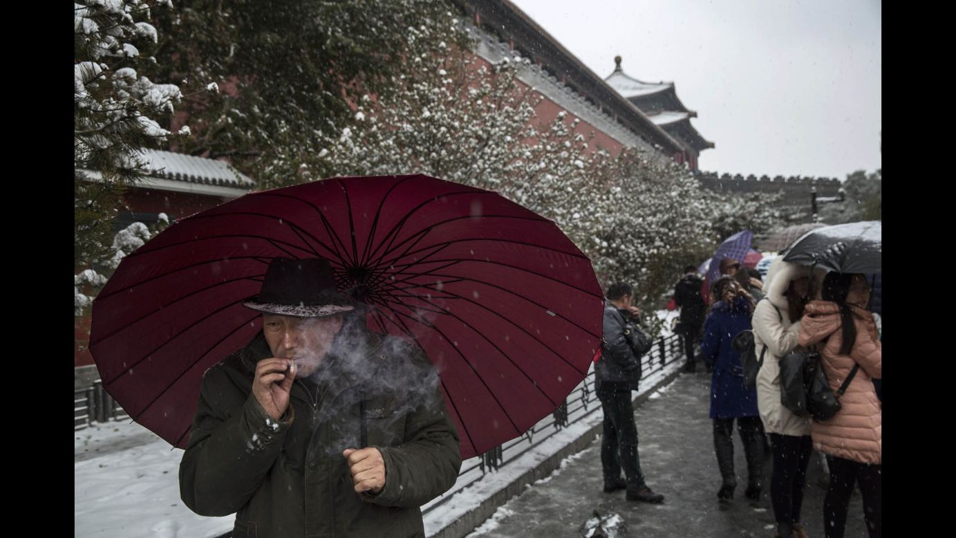 A man smokes as he shields himself from the snow outside the Forbidden City in Beijing.