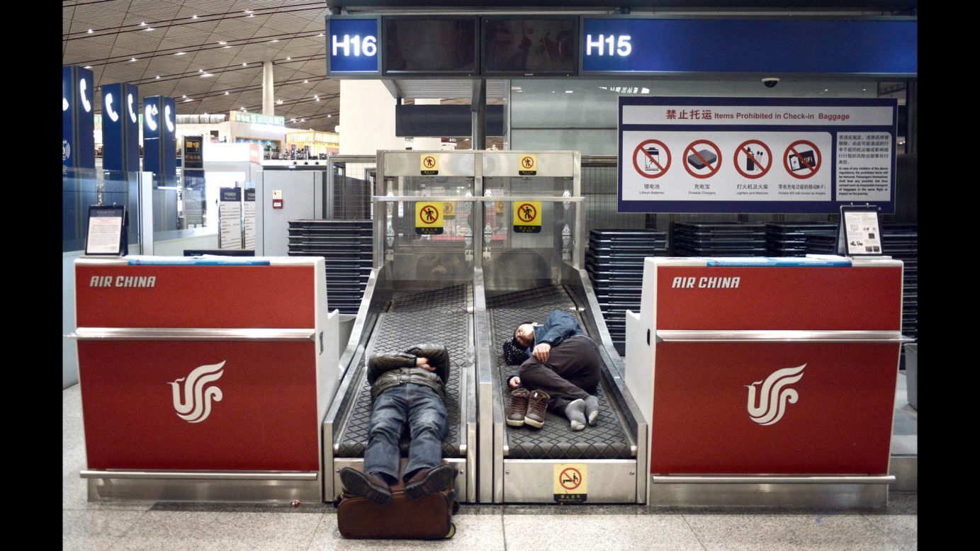 Airline passengers sleep on the check-in conveyor belts at an Air China counter in the Beijing Capital International Airport on November 23 after heavy snow canceled and delayed numerous flights.