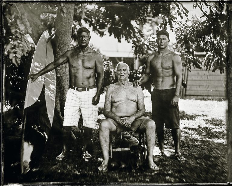 George Downing (seated) is a Hawaiian surfing pioneer, and is the longtime contest director for "the Eddie" -- he decides if the event will take place.<br />His son Keone Downing (left) won the contest in 1989-90, riding a board shaped by his dad. Keone's son Kaohi (right) also surfs, and at one stage played minor league baseball.  