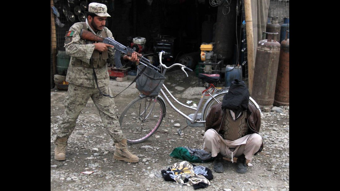 <strong>January 20:</strong> An Afghan security officer aims his weapon at a man who was allegedly planning a suicide bomb attack in Jalalabad, Afghanistan.