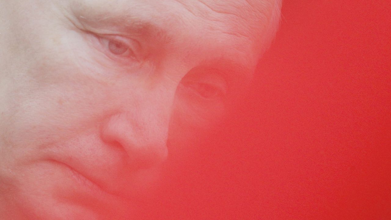 <strong>February 23: </strong>Russian President Vladimir Putin, seen through a red flag, attends a wreath-laying ceremony in Moscow on Defender of the Fatherland Day.