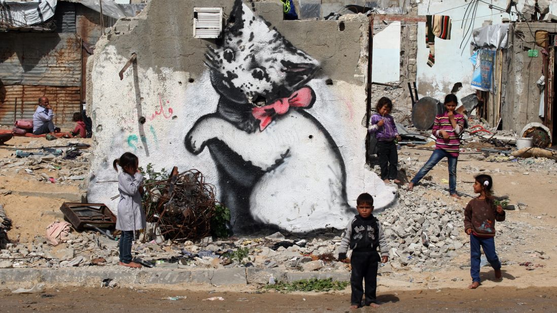 <strong>February 26:</strong> Children stand next to a Banksy mural on the remains of a destroyed house in Beit Hanoun, Gaza. The house was destroyed last year during fighting between Israel and Hamas.<a href="http://www.cnn.com/2013/10/14/living/gallery/banksy-street-artist/index.html" target="_blank"> See more work from Banksy, the anonymous street artist</a>