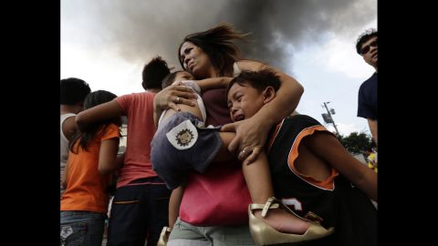 <strong>April 29:</strong> A mother carries her children while their house burns at a residential slum area in Manila, Philippines. The Manila Fire Department said the fire left more than 30 families homeless.