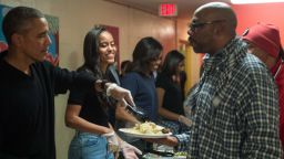 Malia Obama (2nd L), daughter of US President Barack Obama (L), smiles as they serve Thanksgiving dinner to homeless military veterans with First Lady Michelle Obama (3rd L) and daughter Sasha at Friendship Place in Washington, DC, on November 25, 2015. 