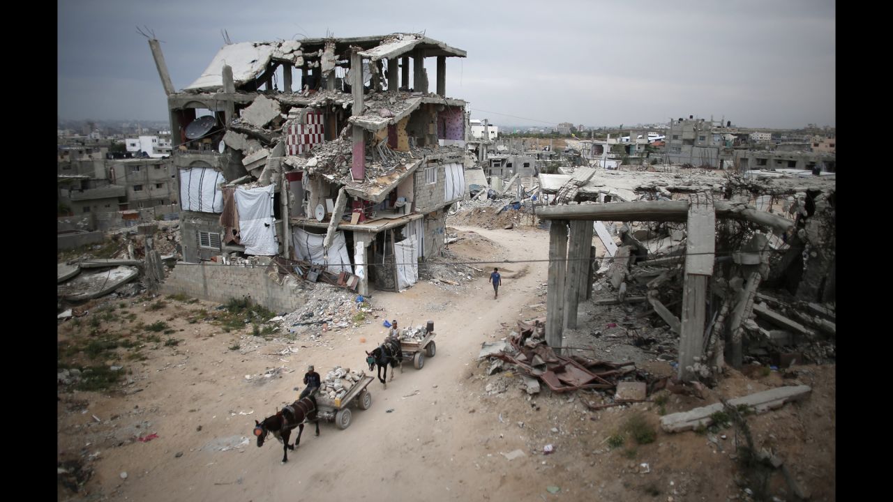 <strong>May 11:</strong> Palestinians ride their donkey carts past destroyed buildings in Gaza City. The buildings were destroyed in 2014 during the 50-day war between Israel and Hamas.