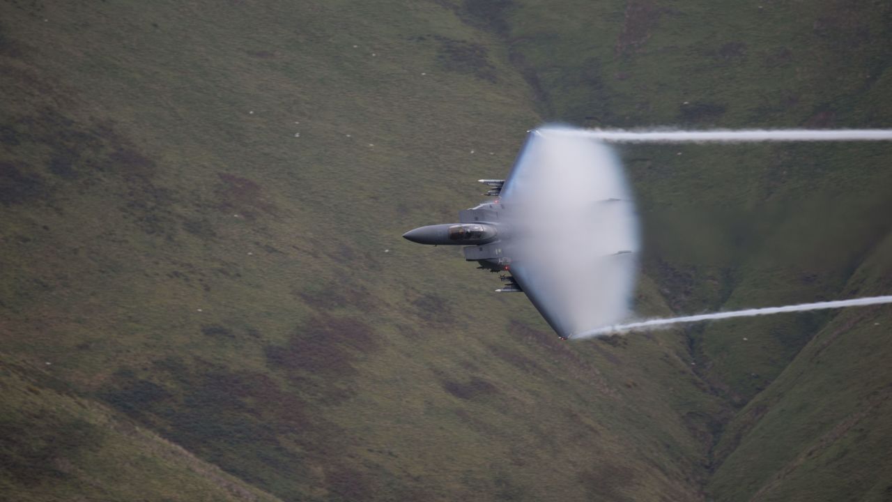 <strong>October 8: </strong>A low-flying jet zooms through a picturesque valley in Wales, leaving a vapor cloud in its wake.