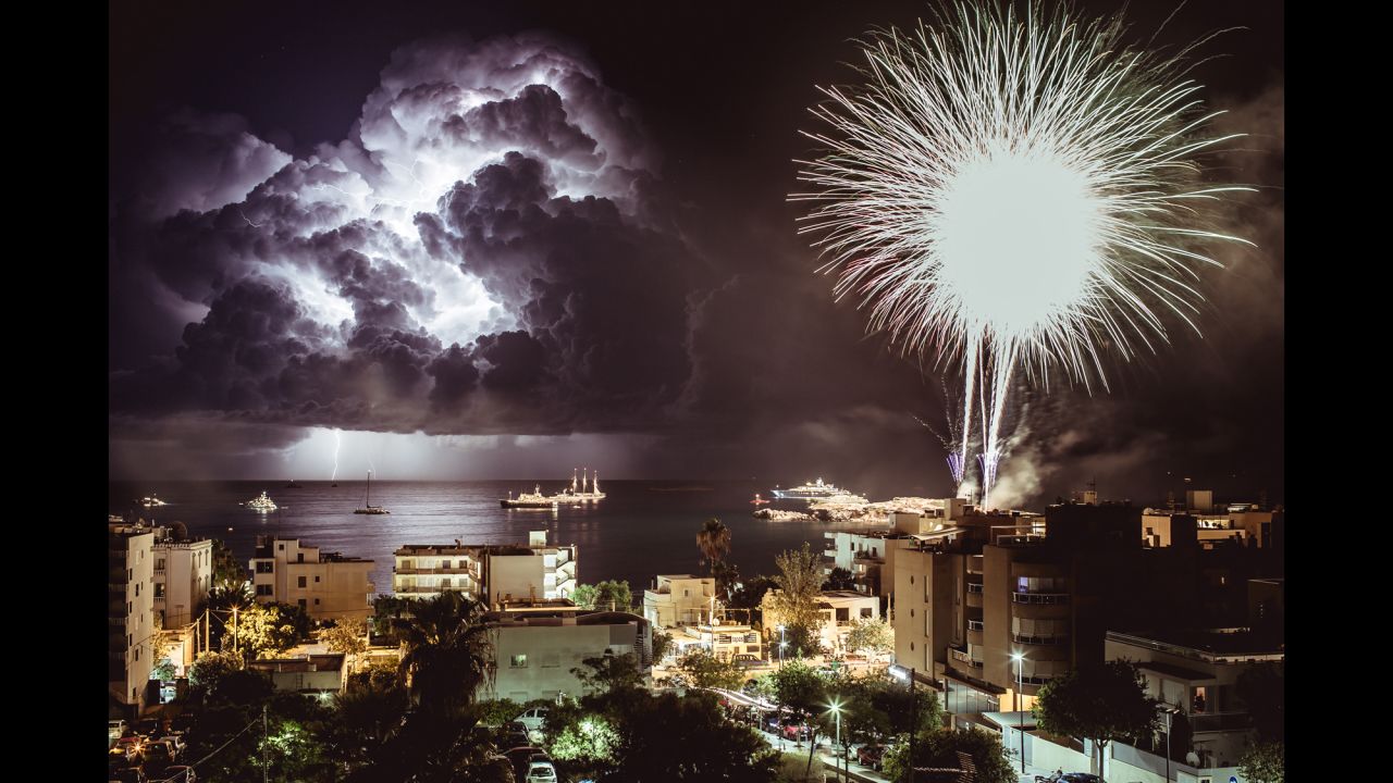 <strong>August 16:</strong> Fireworks explode in Figueretas, Spain, as lightning flashes over the sea.