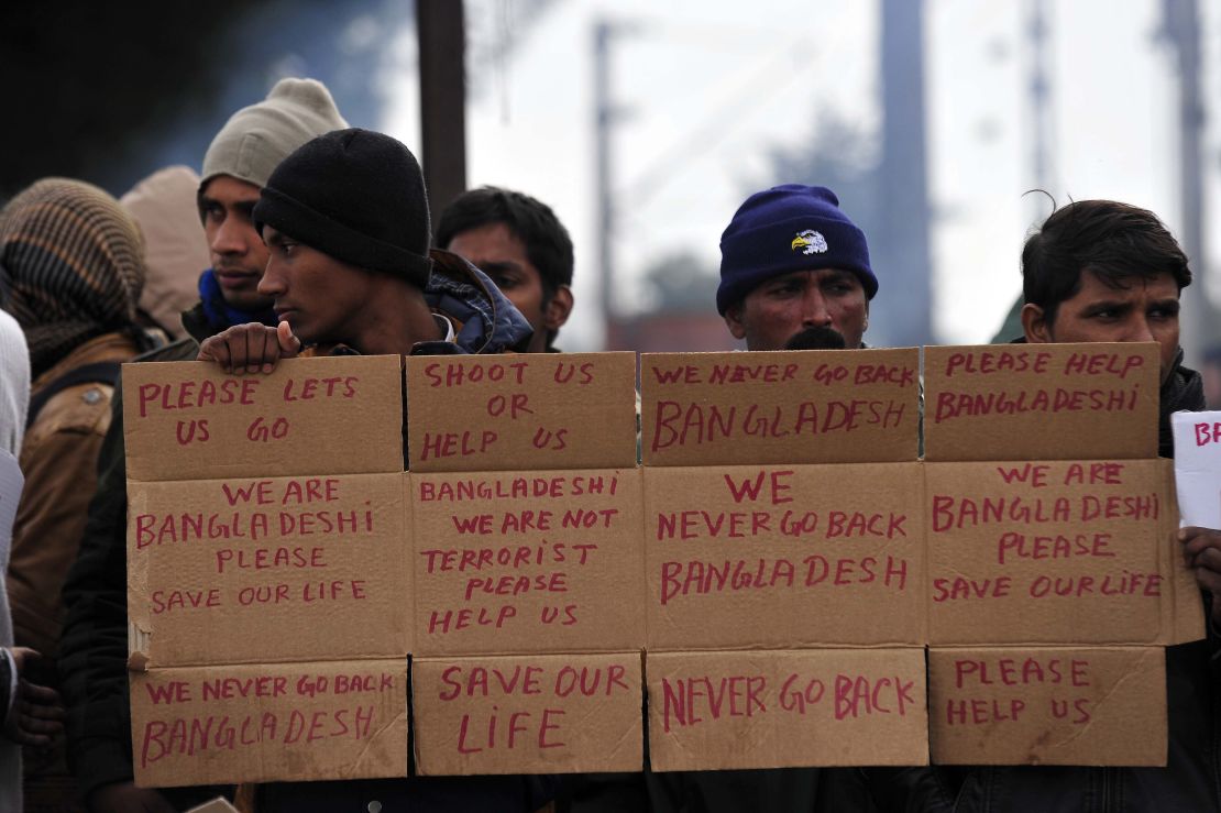 Men from Bangladesh stuck at the Greek-Macedonian border hold up signs pleading for help 