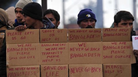 Men from Bangladesh stuck at the Greek-Macedonian border hold up signs pleading for help