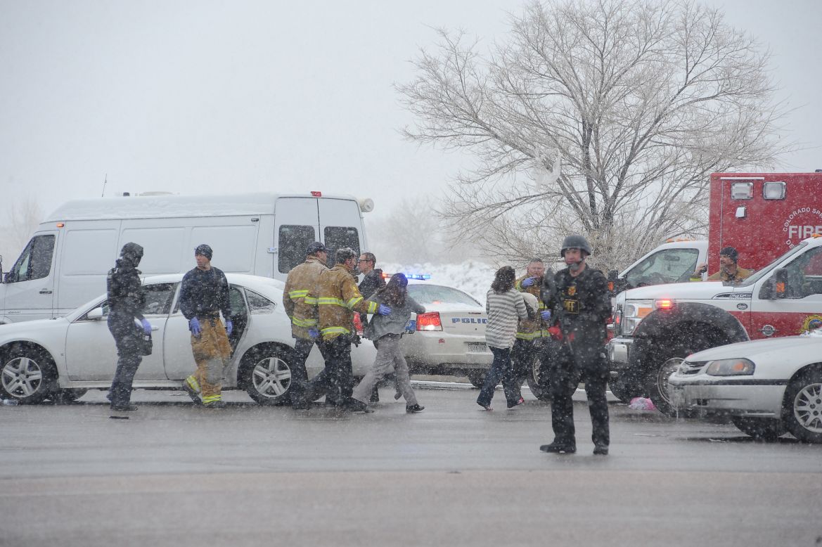 A woman is escorted to an ambulance by police near the scene.