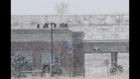 Police sit on the roof of a Chase Bank branch across the parking lot from the scene at Fillmore Street and Centennial Boulevard.