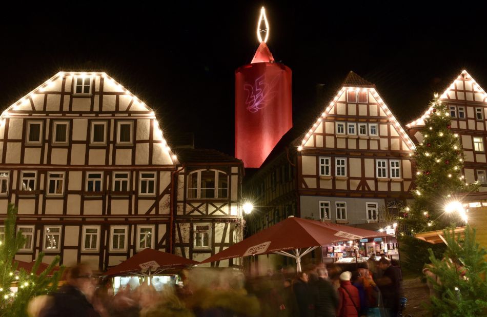 Timber-framed buildings are illuminated in front of a giant candle tower in Schlitz, Germany. The 36-meter (118-foot) tower dominates the Christmas market.