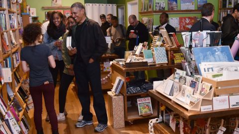 US President Barack Obama taks with manager Anna Thorn while shopping with daughters Malia and Sasha in Upshur Street Books during Small Business Saturday on November 28, 2015, in Washington, DC.