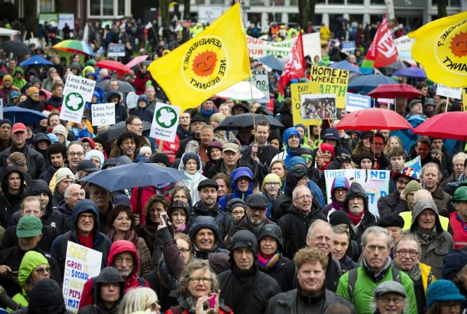 People hold flags and placards while marching in Amsterdam.