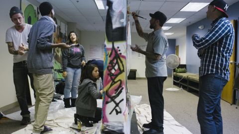 Timm, right, watches TRUE Skool students paint on a makeshift graffiti wall. Sarah Dollhausen, the program's founder and executive director, said, "We hear from a lot of our young people, 'I'm just happy to be alive.' "